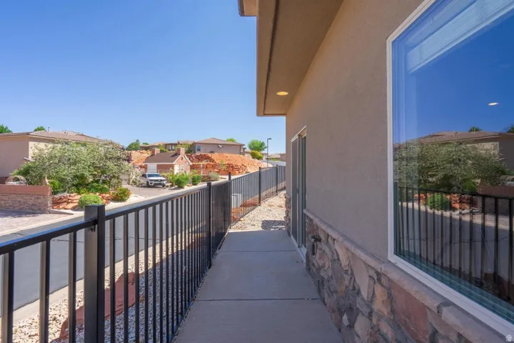 Exterior walkway featuring a stucco facade, stone veneer detailing, and a black wrought iron fence