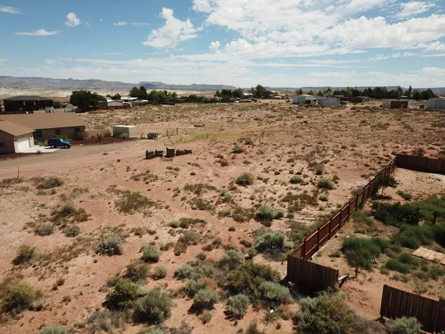 Expansive desert landscape with natural flora, perimeter fencing, and distant mountain backdrops