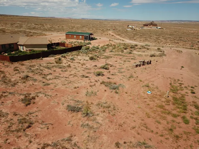 Expansive undeveloped lot featuring a natural desert landscape and distant structures