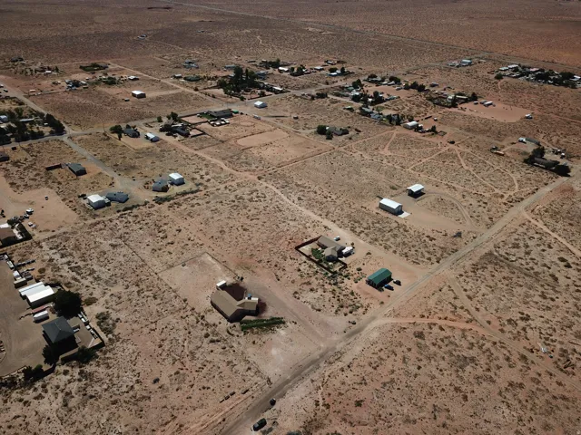 Expansive desert landscape with scattered residential properties, featuring a mix of single-story homes and outbuildings