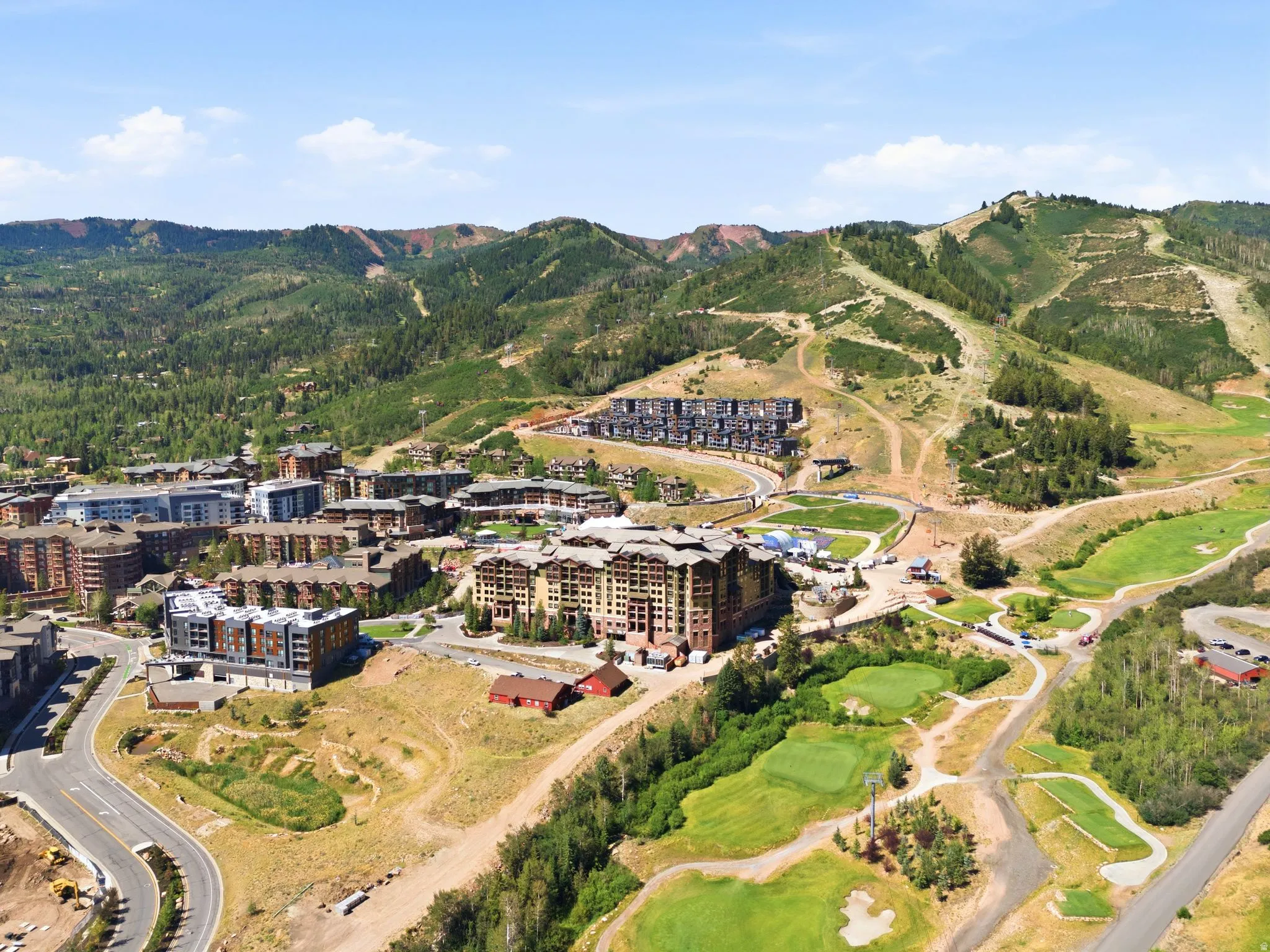 Mountainous landscape featuring multiple structures, ski slopes, and golf course elements