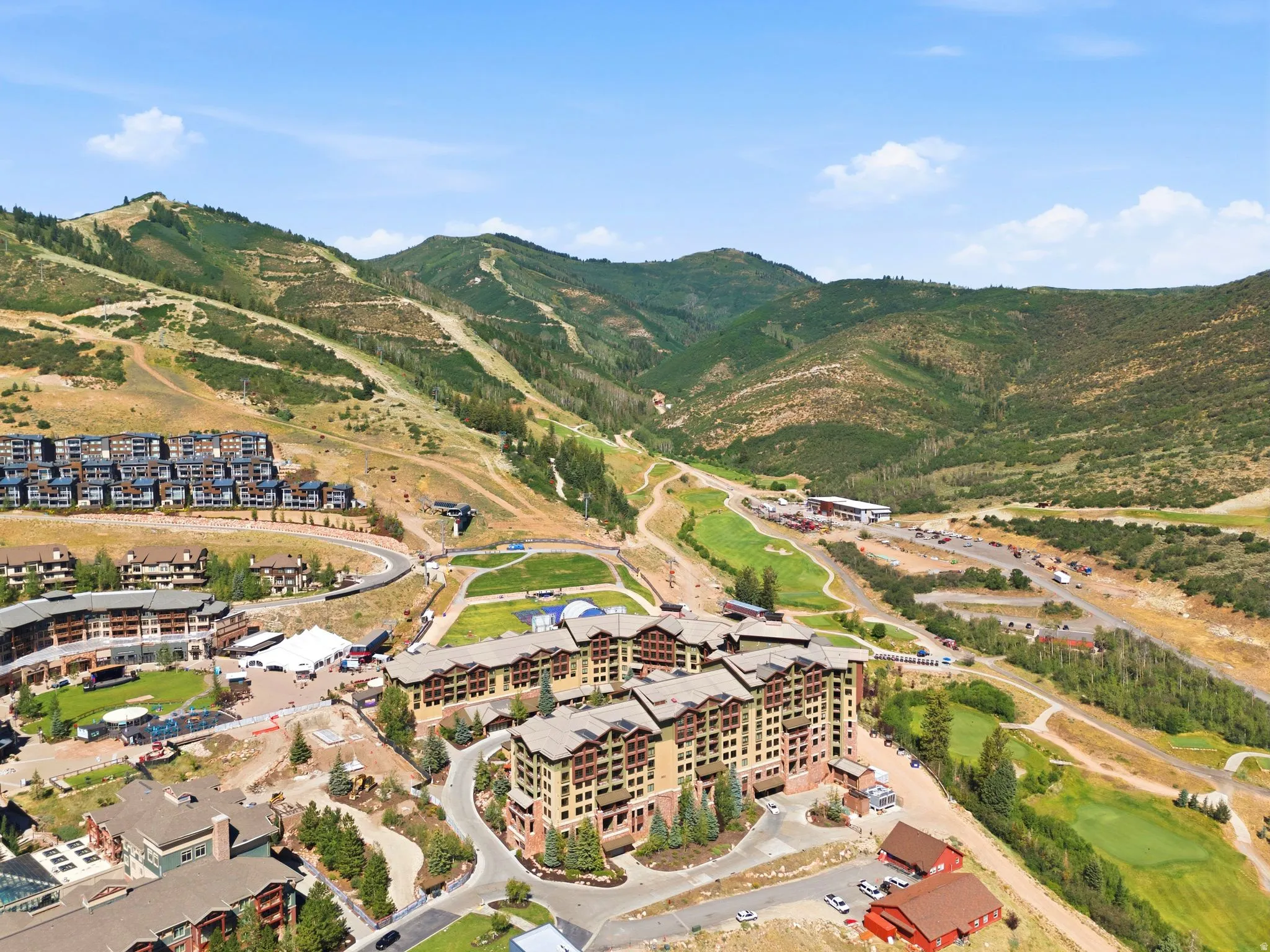 Expansive mountain resort property featuring multiple multi-story buildings with traditional architecture, integrated into a natural, sloped landscape with manicured green spaces and paved pathways