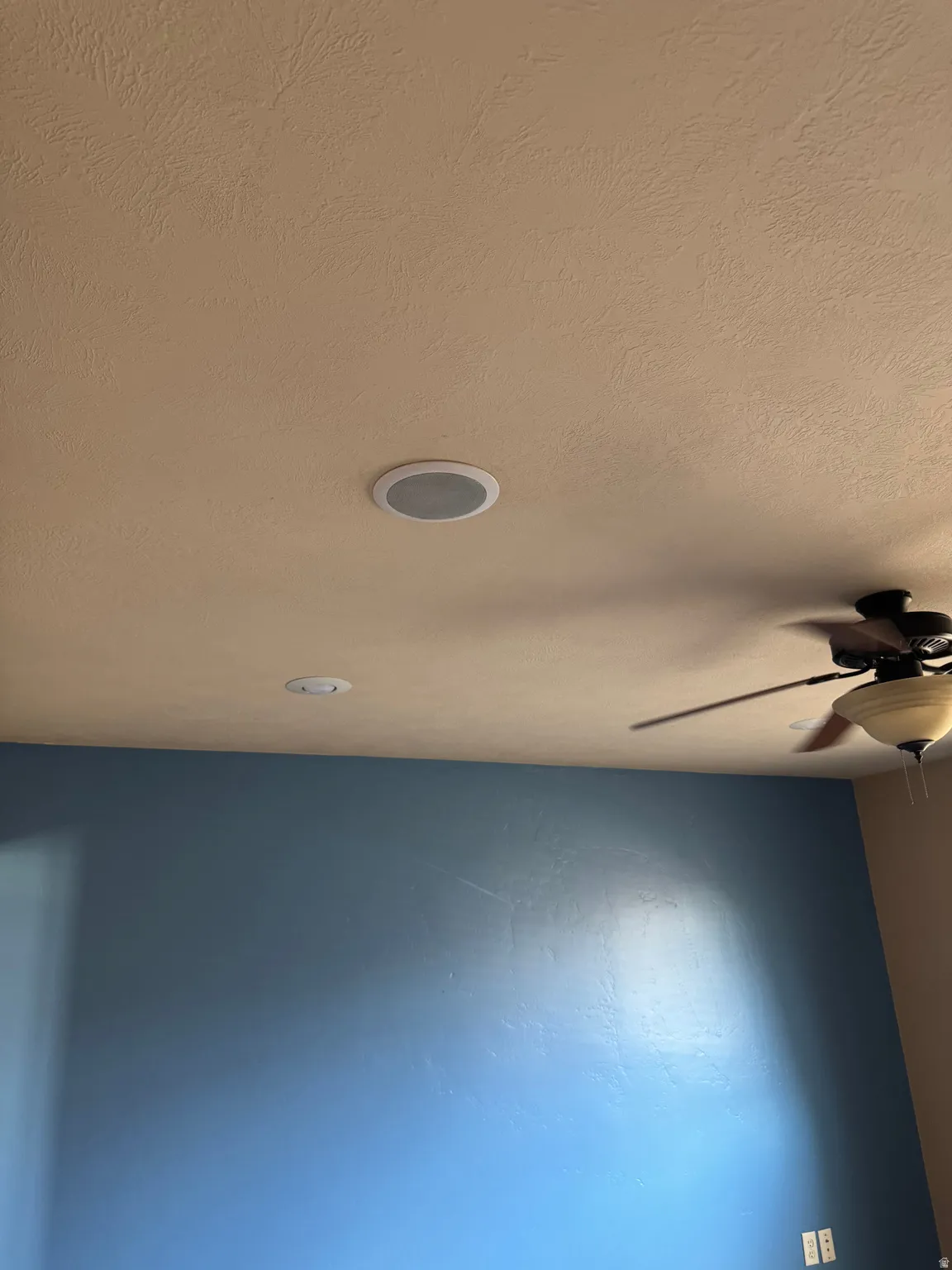 Textured ceiling with recessed lighting and a ceiling fan