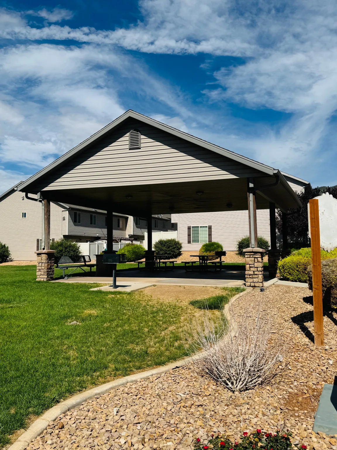 Open-air pavilion featuring a gable roof, vinyl siding, and stone-wrapped columns