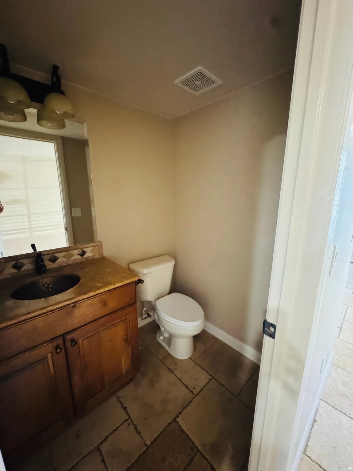 Bathroom featuring a wood-finish vanity with a vessel sink, stone countertop, and decorative backsplash