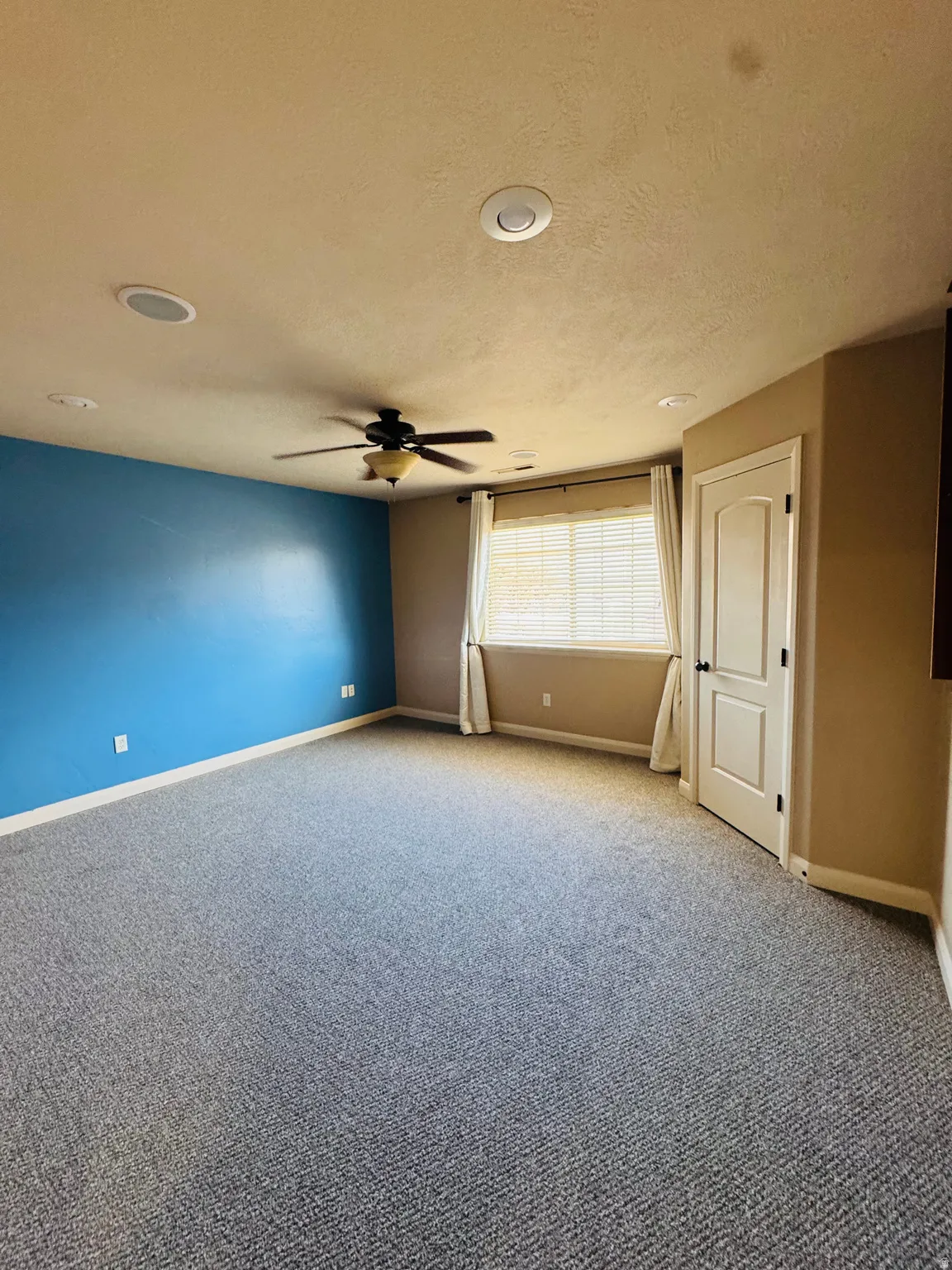 Spacious room featuring gray carpet, a ceiling fan, recessed lighting, and a window with blinds