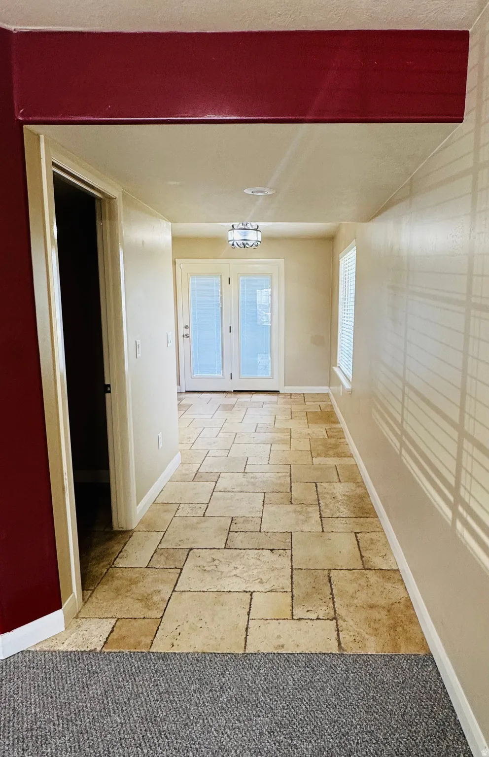 Tiled hallway featuring natural-toned square and rectangular floor tiles