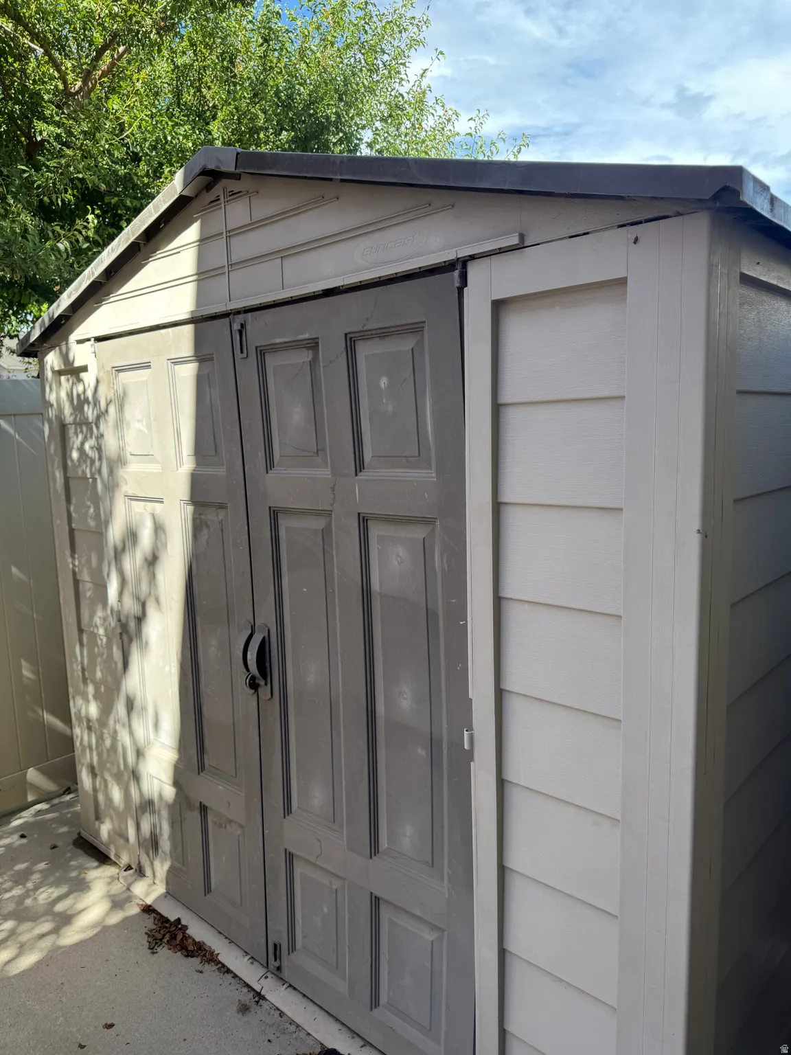 Exterior storage shed featuring a dual-tone finish, a pitched roofline, and double panel doors with a central handle