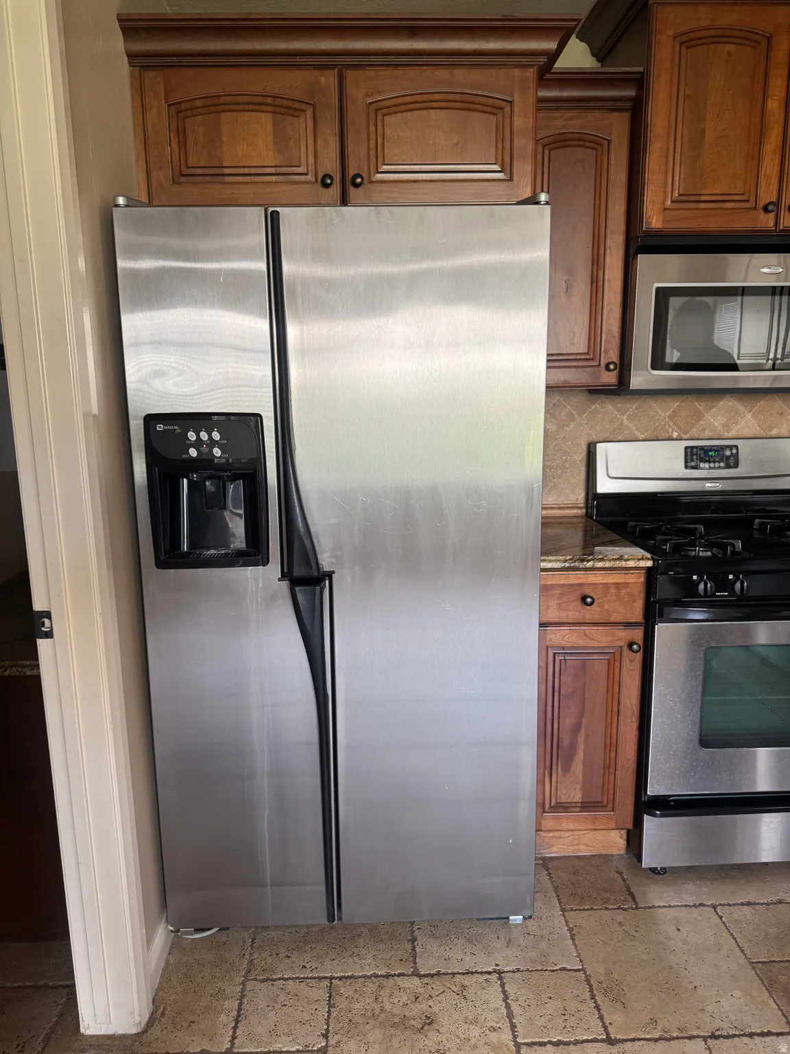 Kitchen featuring a side-by-side stainless steel refrigerator with an external ice and water dispenser, a stainless steel range with a gas cooktop, and a stainless steel over-the-range microwave
