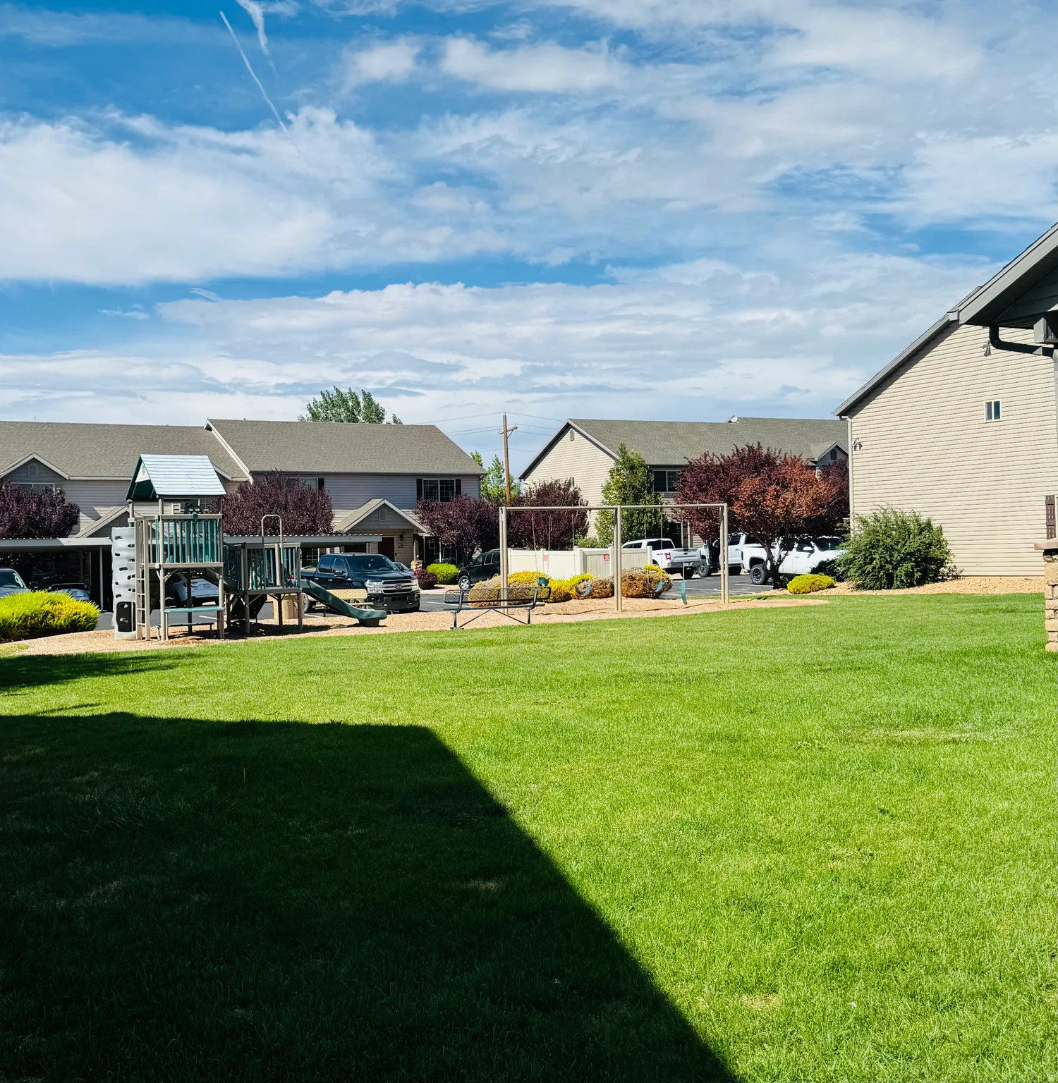 Expansive green lawn area featuring a multi-level playground structure and swing set