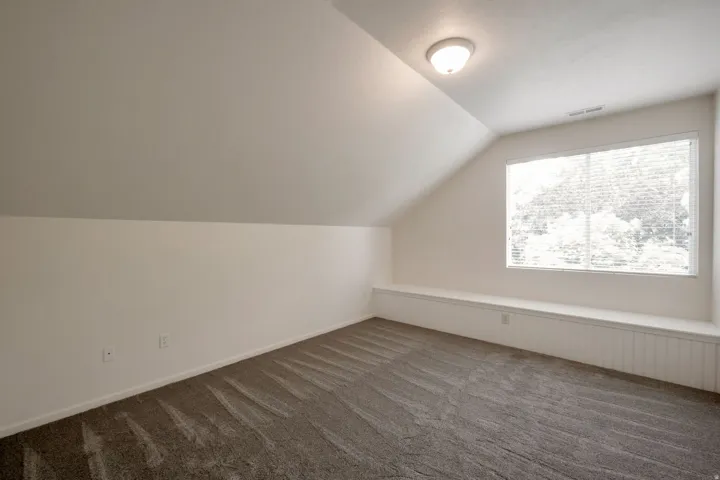 Versatile room featuring an angled ceiling, recessed lighting, and a window with blinds