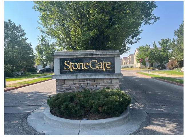 Stone-clad monument signage with gold lettering at the community entrance