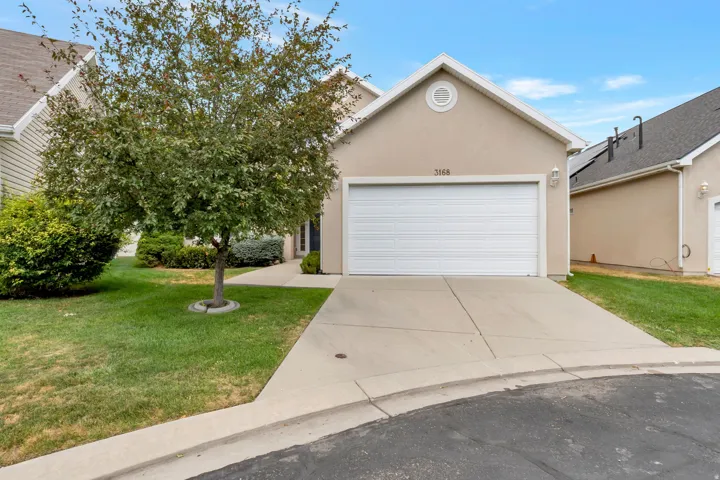Single-story residence featuring a two-car garage with a white sectional door, stucco exterior, and a gabled roofline