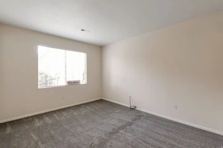 Carpeted room featuring a large window with horizontal blinds, light-colored walls, and white trim