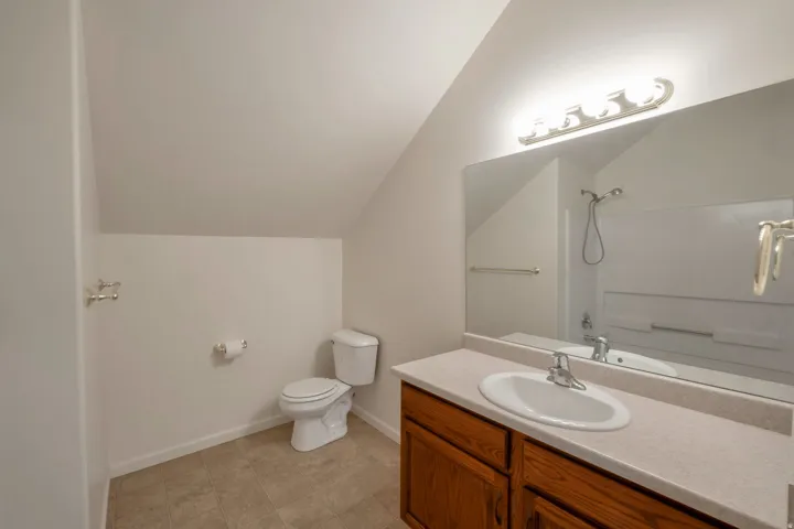 Bathroom featuring a full vanity with wood-finish cabinetry, a built-in sink, and a light-toned countertop