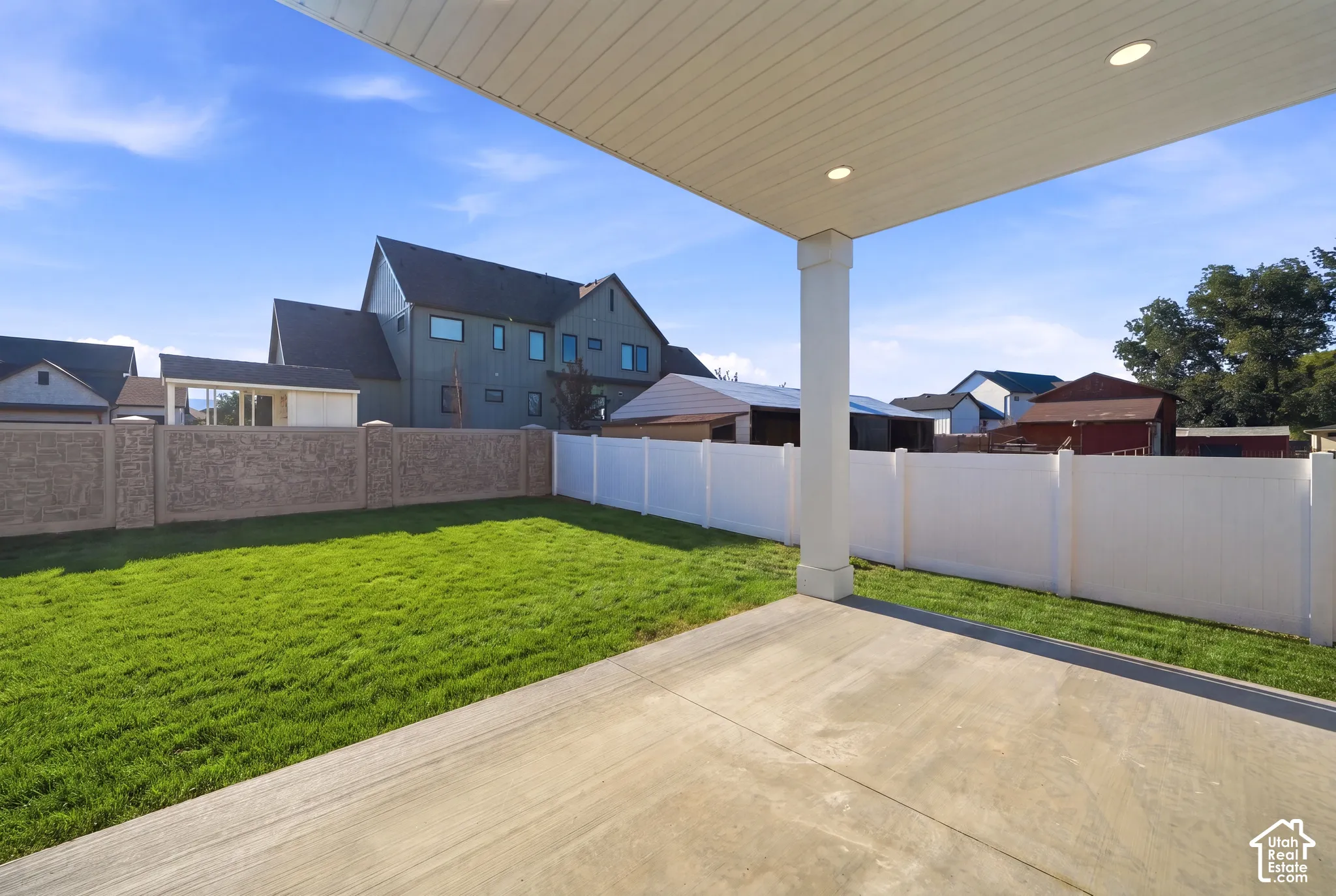 Covered patio with recessed lighting, concrete flooring, a manicured lawn, and perimeter fencing *grass ai generated