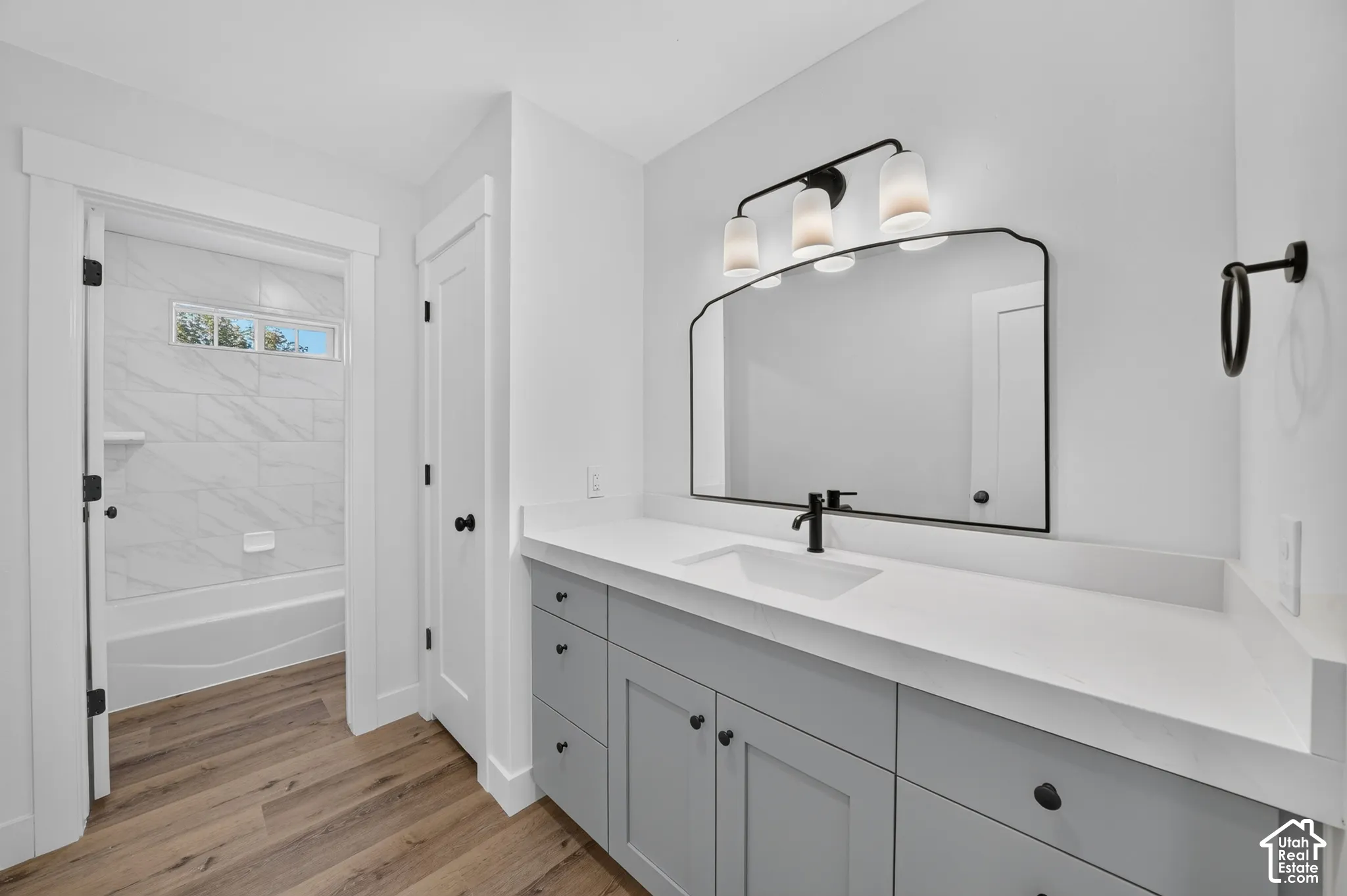 Bathroom featuring a double vanity with gray cabinetry, white countertops, and wood-finish flooring