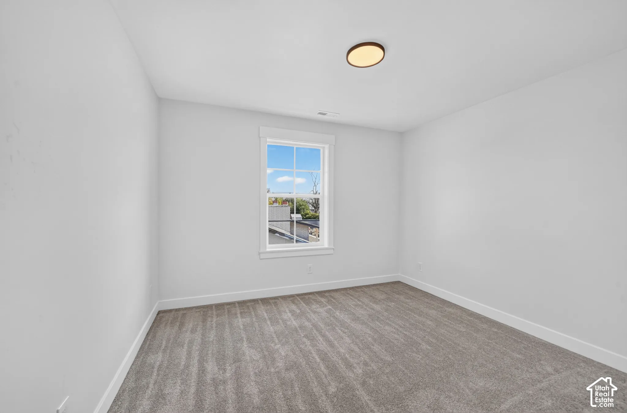 Room with light gray carpeting, white walls, and a single window with white trim