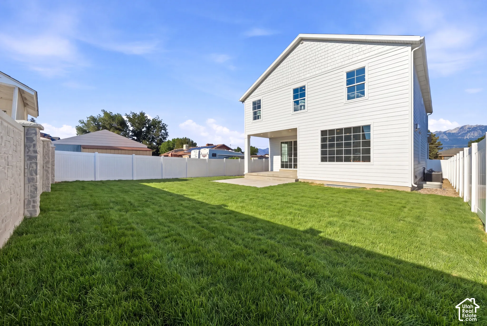 Expansive backyard featuring a manicured lawn, a large concrete patio, and a privacy fence *grass ai generated