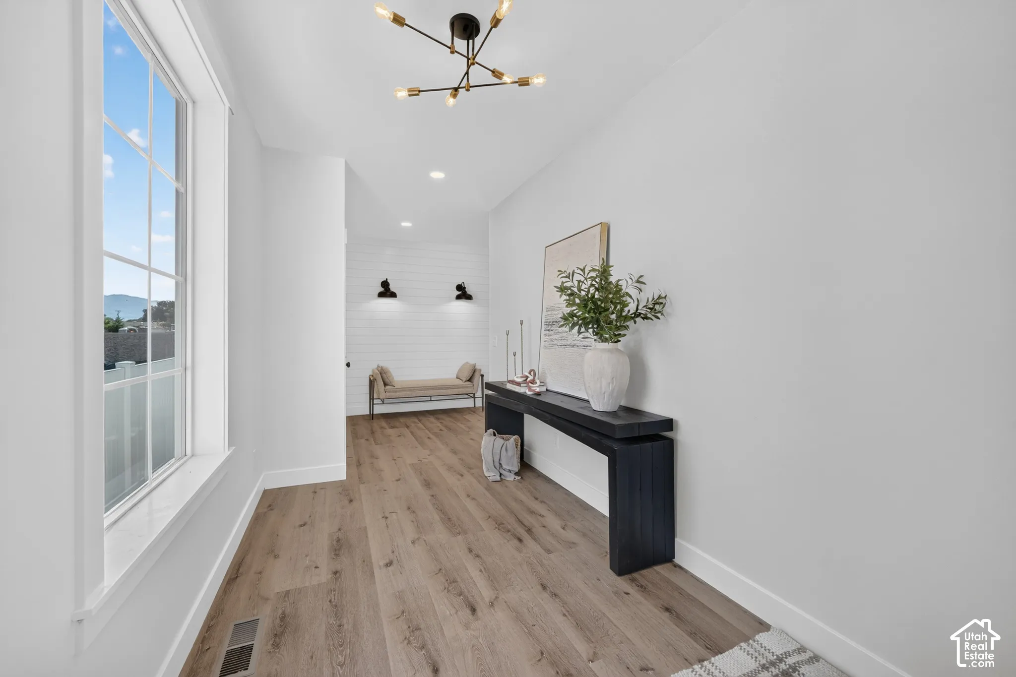 Spacious entryway featuring wood-finish flooring, a contemporary chandelier, and a large window with grid panes