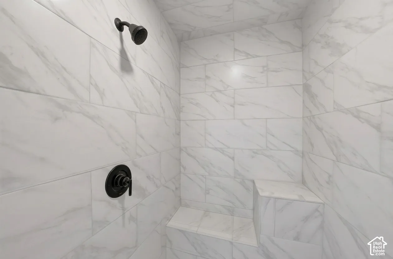 Shower enclosure featuring white marbled tile, a built-in bench, and matte black fixtures