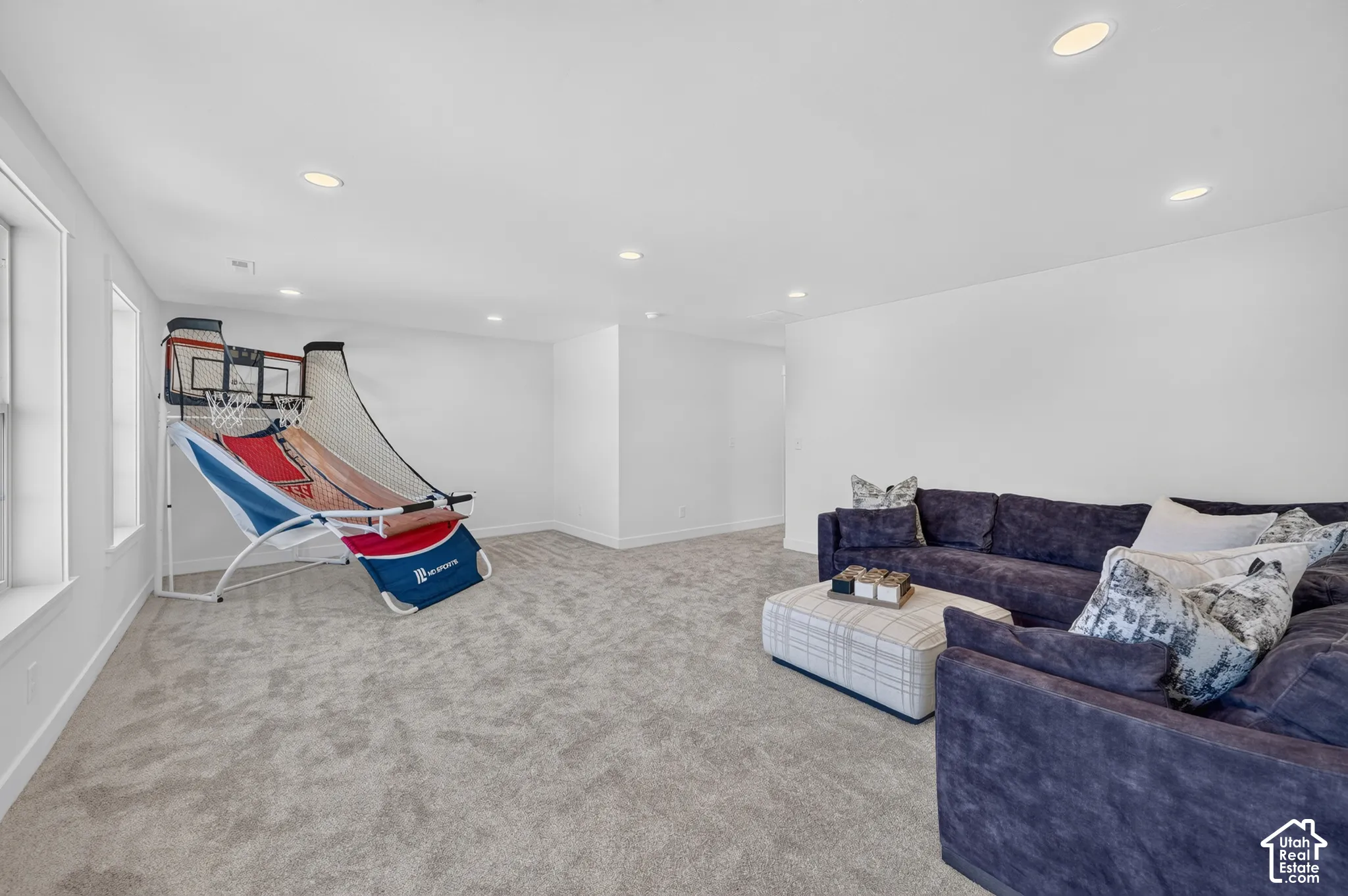 Spacious room featuring light gray carpeting, recessed ceiling lighting, and multiple windows providing natural illumination