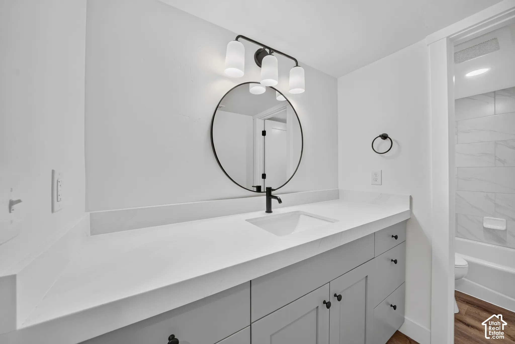 Bathroom vanity featuring a quartz countertop, integrated sink, and matte black faucet