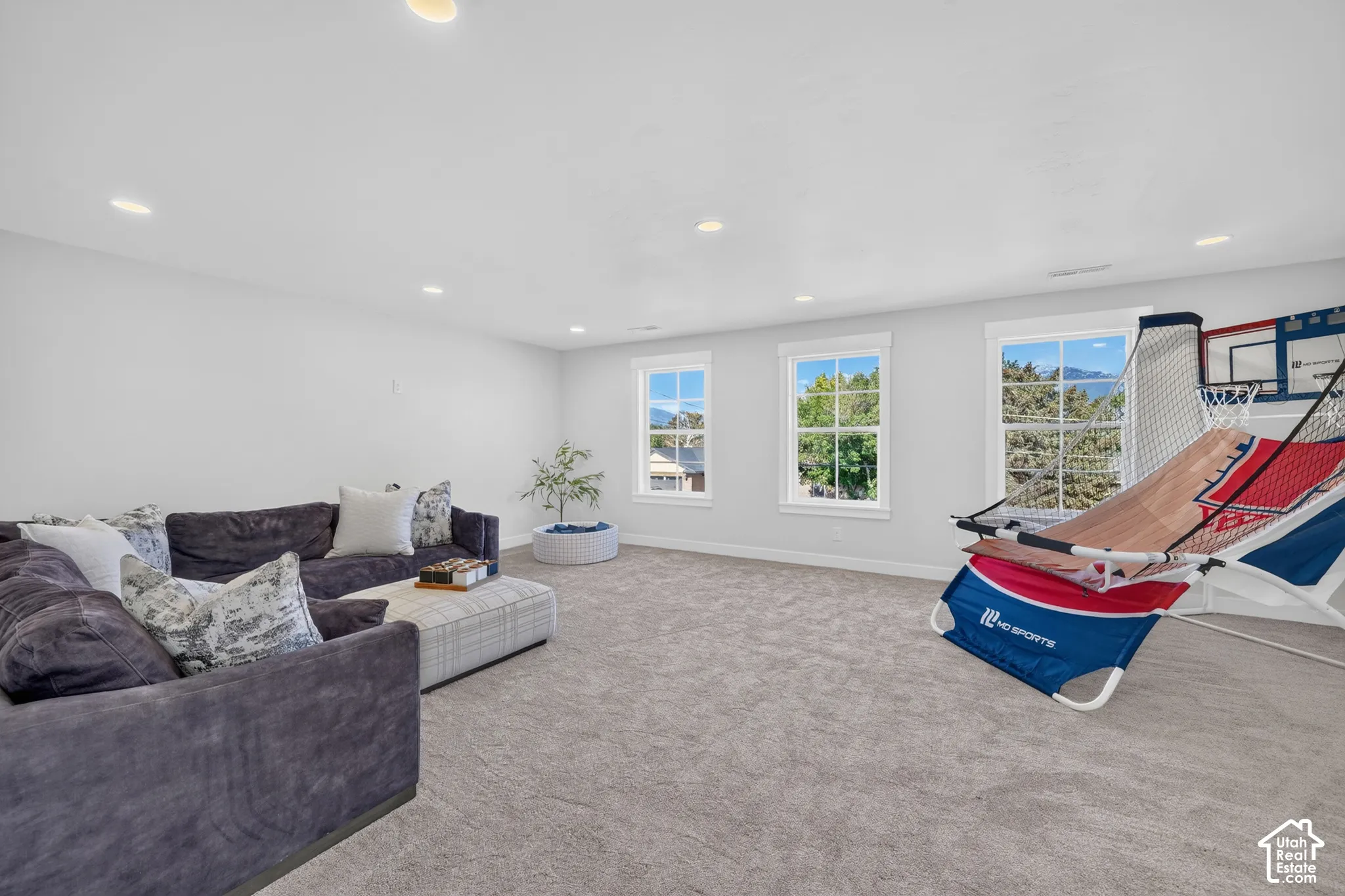Spacious room featuring light gray carpeting, recessed lighting, and white walls
