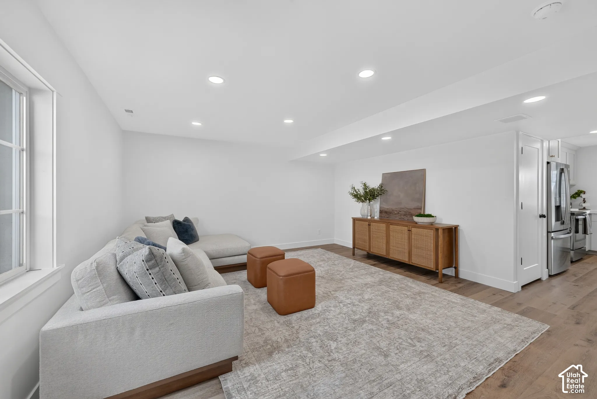 Spacious room featuring wood-finish flooring, recessed lighting, and a window with white trim