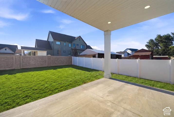 Covered patio with recessed lighting, concrete flooring, a manicured lawn, and perimeter fencing *grass ai generated