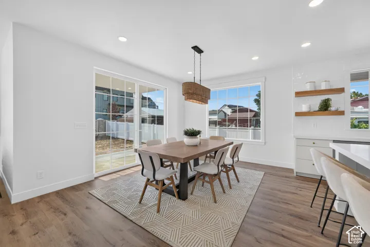 Open-concept dining area featuring wood-finish flooring, recessed lighting, and a woven pendant light fixture