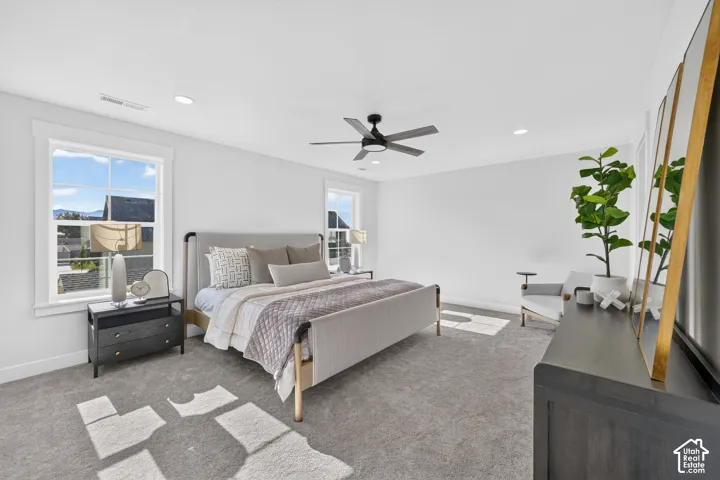 Spacious bedroom featuring light gray carpeting, recessed lighting, and a ceiling fan