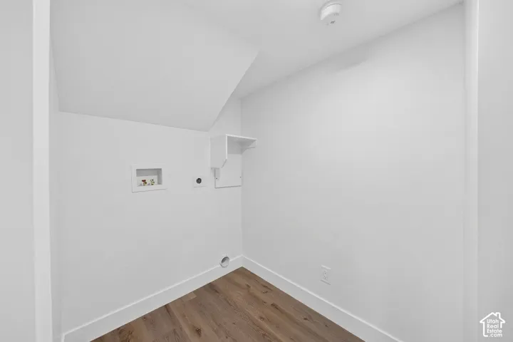 Dedicated laundry area featuring wood-finish flooring, white walls, and a built-in storage shelf