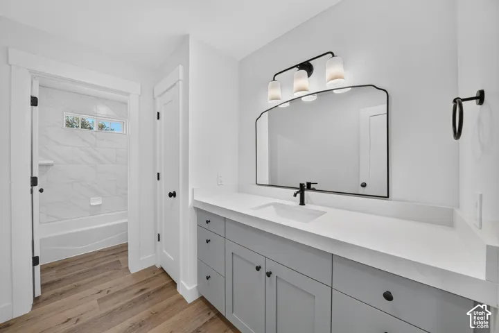 Bathroom featuring a double vanity with gray cabinetry, white countertops, and wood-finish flooring