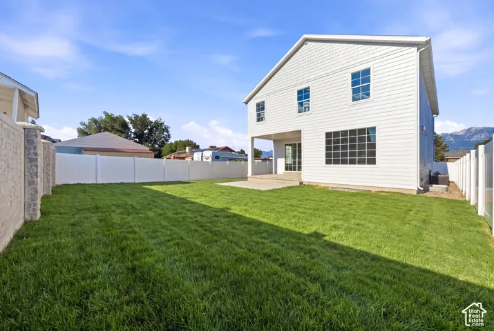 Expansive backyard featuring a manicured lawn, a large concrete patio, and a privacy fence *grass ai generated