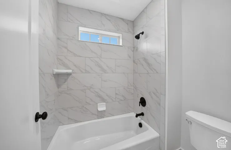 Contemporary bathroom featuring a white bathtub, black fixtures, and marbled tile surround