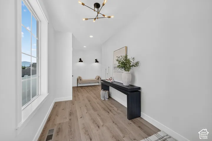 Spacious entryway featuring wood-finish flooring, a contemporary chandelier, and a large window with grid panes