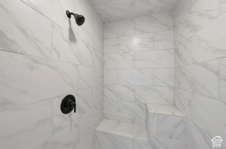 Shower enclosure featuring white marbled tile, a built-in bench, and matte black fixtures
