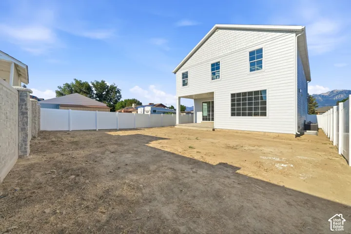 Spacious backyard featuring a new construction home with white siding, a covered patio, and a privacy fence