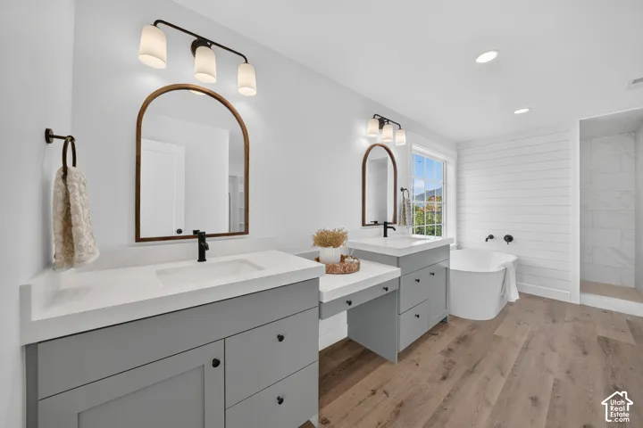 Bathroom featuring dual vanity with gray cabinetry and white countertops, individual arched mirrors, and matte black fixtures
