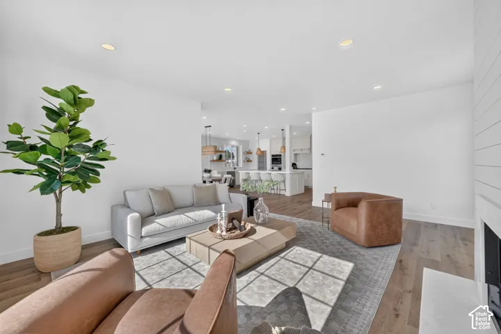 Open-concept living space featuring wood-finish flooring, recessed lighting, and a white shiplap accent wall with a built-in fireplace