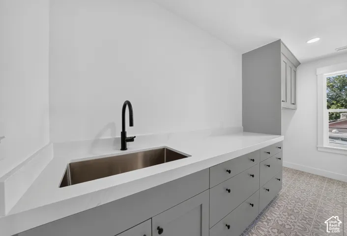 White countertop with an undermount stainless steel sink and matte black faucet