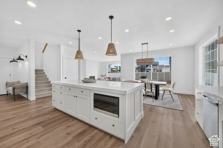 Open-concept living area featuring an expansive kitchen island with a built-in microwave, wood-finish flooring, and recessed lighting