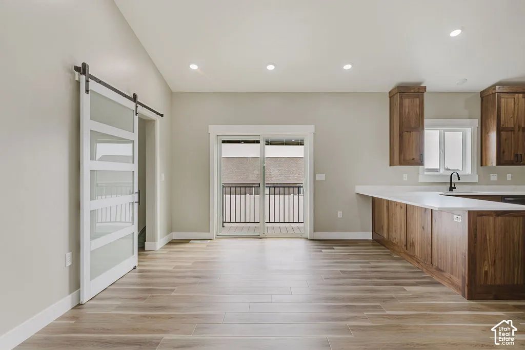 Open-concept living space featuring wood-finish flooring, recessed lighting, and a sliding glass door leading to an exterior balcony with black iron railings