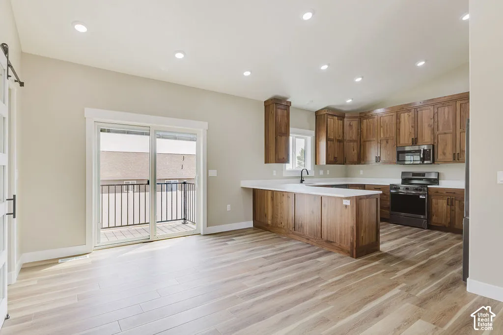 Open-concept kitchen and living area featuring wood-finish flooring, recessed lighting, and a modern kitchen with wood cabinetry