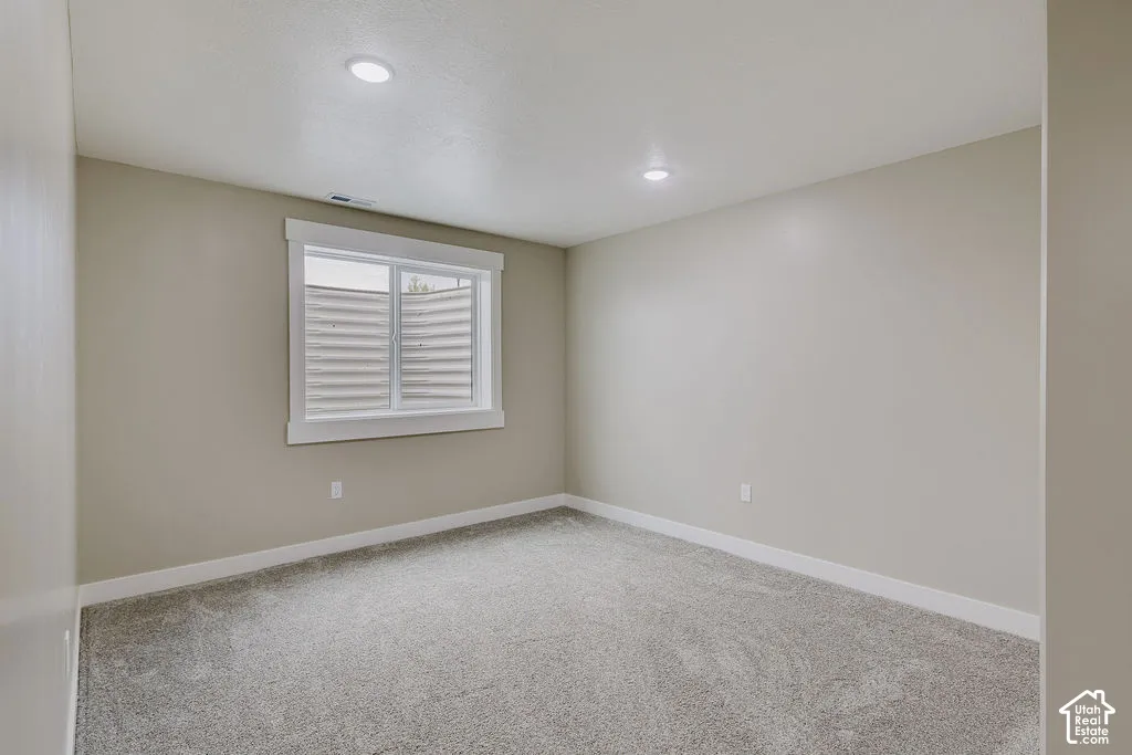 Carpeted room featuring a white-trimmed window, recessed ceiling lights, and light-toned wall paint