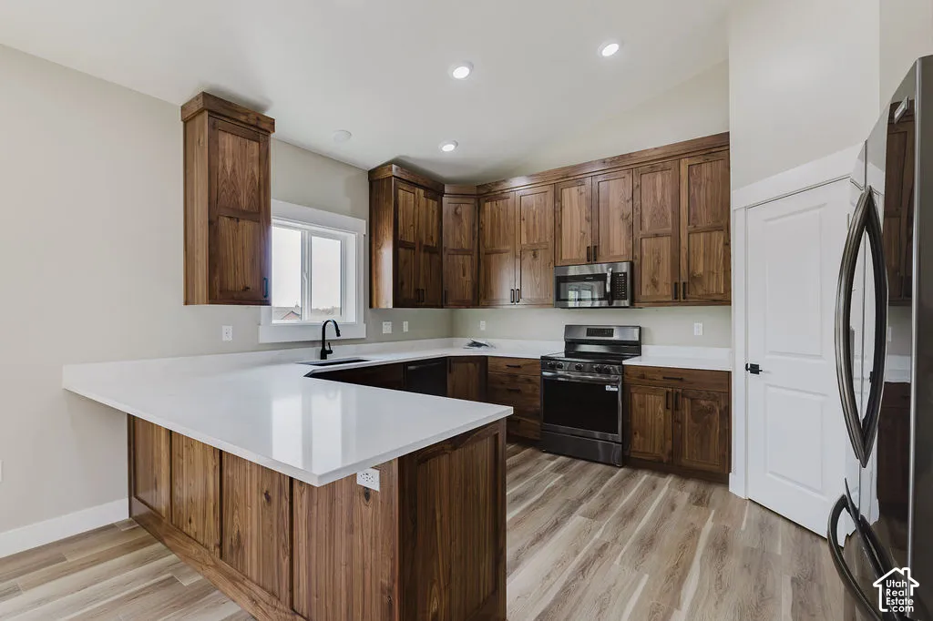 Kitchen featuring extensive wood cabinetry, white countertops, stainless steel appliances, and wood-finish flooring