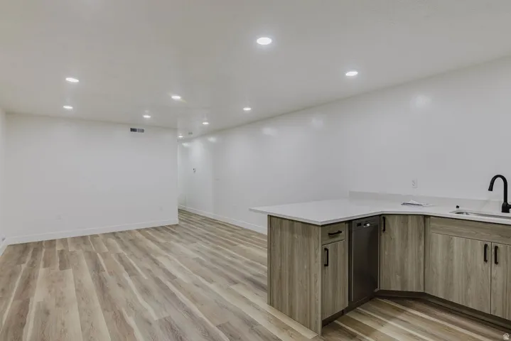 Spacious room with wood-finish flooring, recessed lighting, and white walls