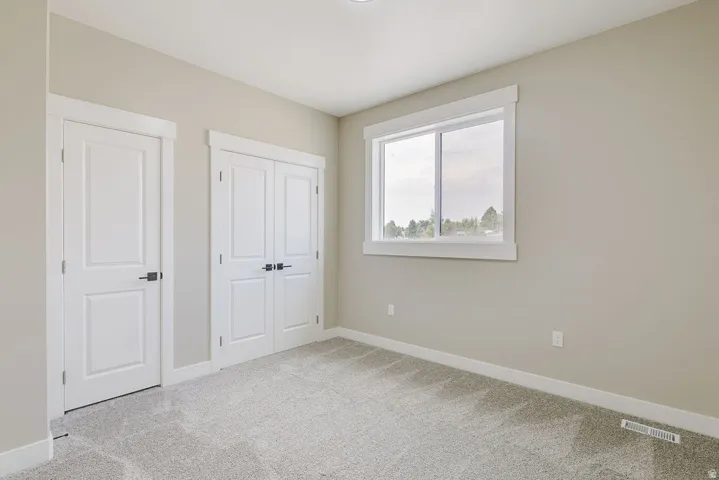 Neutral-toned walls complement plush grey carpeting