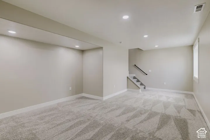 Spacious room featuring neutral-toned walls, recessed lighting, and patterned carpeting